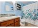 Bright bathroom with a floral shower curtain, decorative shelves, and mosaic backsplash at 4705 Andes St, Denver, CO 80249