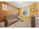 Cozy Bedroom features a gray crib, rocking chair, and decor on orange walls, creating a warm and inviting space at 4705 Andes St, Denver, CO 80249