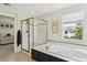 Bright bathroom with a glass enclosed shower and large tub by a window, with natural light at 10832 Montvale Cir, Highlands Ranch, CO 80130