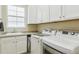 Bright laundry room with white cabinets, sink, granite counters, and modern front-load washer and dryer at 10832 Montvale Cir, Highlands Ranch, CO 80130