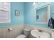 Light-filled powder room with blue walls, white wainscoting, and stylish fixtures at 1382 Raindrop Way, Castle Rock, CO 80109