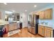 Charming kitchen featuring wood cabinets, stainless steel appliances, and an open view to the living area at 2556 E 131St Pl, Thornton, CO 80241