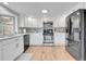 Bright kitchen with stainless appliances, wood floors, light gray backsplash and white cabinets at 5050 W 102Nd Ave, Westminster, CO 80031