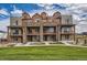 Modern townhome exterior with stone accents, balconies, and lush green lawn under a partly cloudy, bright blue sky at 9629 Browns Peak Cir, Littleton, CO 80125