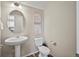 Well-lit half bath with a pedestal sink, oval mirror, and contemporary floral prints at 11650 Park South Ln, Parker, CO 80138