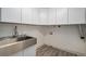 Well-lit laundry room with stainless steel sink, modern cabinets, and wood-look flooring at 19334 E Prentice Pl, Centennial, CO 80015