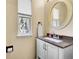 Powder room featuring granite counters, stylish white vanity, and a decorative round mirror at 7835 Canvasback Cir, Littleton, CO 80125