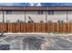 Back exterior view with a wooden fence, patio umbrellas, and parking area at 3614 W Radcliff Ave, Denver, CO 80236