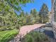 Lush backyard featuring a stone patio with pergola and seating, surrounded by mature trees and landscaping at 24487 E Frost Dr, Aurora, CO 80016
