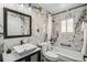 Modern bathroom featuring stylish marble tiling, white vanity and fixtures, and a shower-tub combo at 6190 Garrison St, Arvada, CO 80004