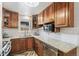 Traditional kitchen with granite countertops, wood cabinets, stainless steel dishwasher, and stylish tile flooring at 6190 Garrison St, Arvada, CO 80004