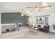Bright living room featuring carpet, many windows, two ceiling fans, gray accent wall, and staircase at 6190 Garrison St, Arvada, CO 80004