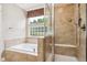 Bright bathroom featuring a tub, shower, and window at 8225 W 67Th Pl, Arvada, CO 80004