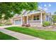Charming brick home with a well-manicured lawn, a covered porch, and a two-car garage at 8225 W 67Th Pl, Arvada, CO 80004