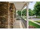 Inviting covered front porch with brick facade, white pillars, and colorful flower beds at 8225 W 67Th Pl, Arvada, CO 80004