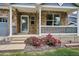Inviting covered front porch with brick facade, white pillars, and colorful flower beds at 8225 W 67Th Pl, Arvada, CO 80004