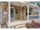Inviting covered front porch with brick facade, white pillars, and colorful flower beds at 8225 W 67Th Pl, Arvada, CO 80004