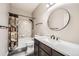 Well-lit bathroom with a shower-tub combo, black fixtures, round mirror, and modern white countertop at 334 Octillo St, Brighton, CO 80601