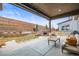 Relaxing covered back patio with stone fireplace, outdoor seating, and tiered landscaping at 7875 S Grand Baker St, Aurora, CO 80016