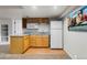 Basement kitchenette with white refrigerator, wood cabinets, granite counters, and light wood-look floor at 634 E 130Th Way, Thornton, CO 80241