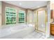 Bright bathroom with a tub beneath windows and a glass enclosed shower at 634 E 130Th Way, Thornton, CO 80241