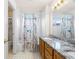 Bright bathroom featuring tiled walls, granite countertop vanity, tub/shower combo and checkered floor at 634 E 130Th Way, Thornton, CO 80241