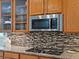 Updated kitchen features stylish mosaic backsplash, granite countertops, and stainless steel microwave at 10371 Knollside Dr, Parker, CO 80134