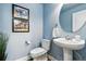 Powder room featuring pedestal sink, round mirror, and blue accent wall at 2949 Emporia Ct, Denver, CO 80238