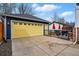 Detached garage with a bright yellow door and ample parking space on a paved driveway at 2949 Emporia Ct, Denver, CO 80238