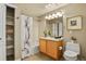 Well-lit bathroom featuring a shower-tub combo, oak vanity, large mirror, and built in shelving at 5537 Lewis Ct # 101, Arvada, CO 80002