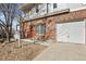 A brick townhouse boasts an attached garage and a vibrant red door adding a pop of color at 5537 Lewis Ct # 101, Arvada, CO 80002