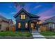 Charming two-story home with dark exterior paint, front porch, landscaped yard, and blue and orange sky at dusk at 2351 N Emerson St, Denver, CO 80205