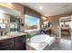 Bright and airy main bathroom featuring a soaking tub, large window, dark cabinets, and granite countertops at 3392 Homestead Dr, Longmont, CO 80504