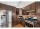 Well-equipped kitchen with stainless steel appliances and dark wood cabinets against a brick wall at 2812 W Davies Dr, Littleton, CO 80120