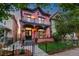 Charming two-story pink home with a lovely wrought iron fenced yard and flowering planters on porch at 2721 Curtis St, Denver, CO 80205