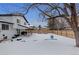 Snowy backyard with a swing set and raised garden beds at 7513 E Bates Dr, Denver, CO 80231