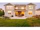 Spacious backyard with a patio, outdoor dining, stone fireplace, and lush lawn creates an inviting outdoor living space at 2258 Front Range Rd, Erie, CO 80516