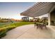 Covered patio boasts an outdoor dining set and views of the backyard, community playground, and sunset horizon at 2258 Front Range Rd, Erie, CO 80516