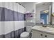 Full bathroom with striped shower curtain, floating shelves, and a vanity with blue backsplash at 2258 Front Range Rd, Erie, CO 80516
