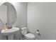 Simple bathroom featuring a pedestal sink, toilet and round mirror above sink at 2258 Front Range Rd, Erie, CO 80516