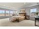 Bright main bedroom featuring neutral tones, tray ceilings, large windows and a seating area at 2258 Front Range Rd, Erie, CO 80516