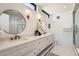 Modern bathroom featuring a dual vanity, round mirrors, and a glass-enclosed shower at 372 S Humboldt St, Denver, CO 80209