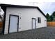 This detached garage has white siding, three entry doors, and a black roof at 1450 Syracuse St, Denver, CO 80220