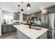 This kitchen boasts gray cabinetry, a stainless steel refrigerator, and a large island with a sink and modern faucet at 1450 Syracuse St, Denver, CO 80220