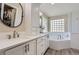 Primary bathroom featuring double vanity, quartz countertops and a soaking tub under a glass-block window at 10487 Panther Trce, Lone Tree, CO 80124