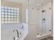 Bright, modern bathroom featuring a soaking tub, glass-block window, and walk-in shower at 10487 Panther Trce, Lone Tree, CO 80124