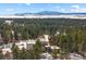 Breathtaking aerial view of a modern home surrounded by a lush forest, with snow-capped mountains in the distance at 367 Sandy Hollow Trl, Franktown, CO 80116