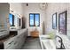 This bathroom has a modern vanity, bathtub, chandelier, brick wall, and dark wood floors at 367 Sandy Hollow Trl, Franktown, CO 80116