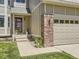 Inviting home entrance with a charming brick pillar, address display, and a well-maintained lawn at 7659 Lebrun Ct, Lone Tree, CO 80124