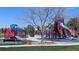 Modern playground equipment with slides, climbing structures, and a basketball court surrounded by lush green grass at 7659 Lebrun Ct, Lone Tree, CO 80124